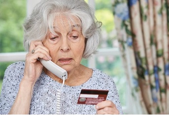 image of elderly on the phone with a credit card